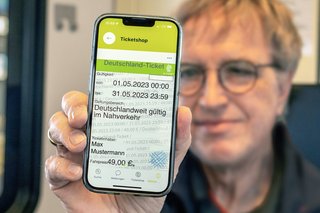 Eine Bahnkundin zeigt ihr digitales Deutschlandticket auf dem Handy vor.