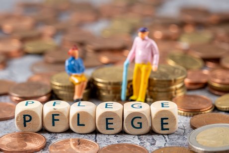 Seniorenfigürchen sitzen auf Münzstapeln, davor bilden Buchstabenwürfel das Wort Pflege