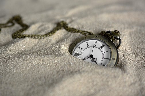 Eine Taschenuhr liegt im Sand.
