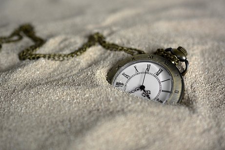 Eine Taschenuhr liegt im Sand.