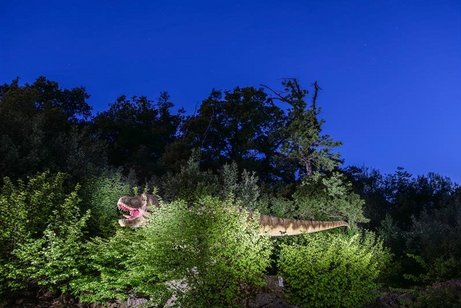 Ein Dinosaurier versteckt sich hinter einem Geb&uuml;sch.