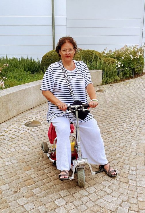 Eine Frau auf einem dreirädrigen Elektroroller.