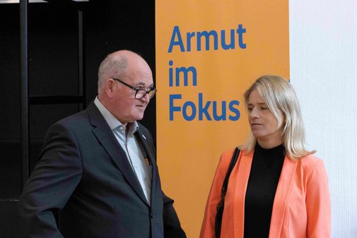 Ein Mann und eine Frau stehen vor einem Roll-Up mit der Aufschrift: Armut im Fokus.