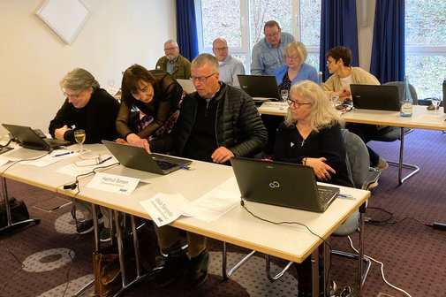 Frauen und M&auml;nner arbeiten mit PCs an Tischen.