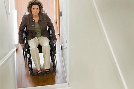 Eine Frau im Rollstuhl steht am Fuße einer langen, steilen Treppe.