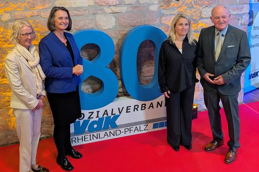 Drei Frauen und ein Mann stehen vor einer aufgestellten 80.