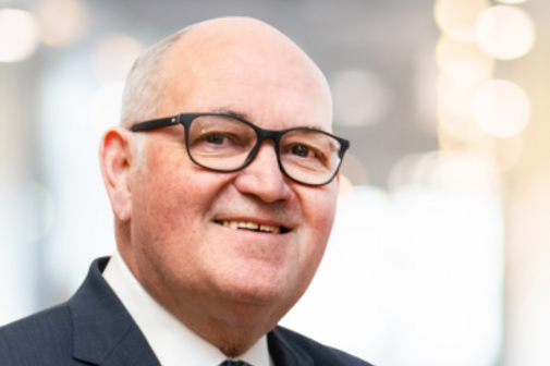 Portr&auml;tbild von einem Mann. Er tr&auml;gt eine Brille und einen Anzug.