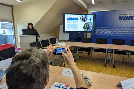 Ein Mann macht ein Foto mit seinem Handy von einer Präsentation.