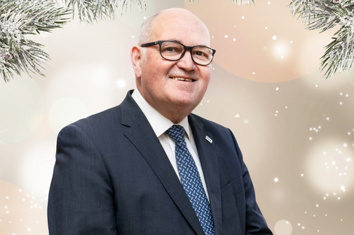 Ein Mann im Anzug vor einem weihnachtlichen Hintergrund.