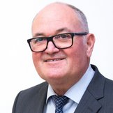 Ein Mann mit Brille im Anzug l&auml;chelt in die Kamera.