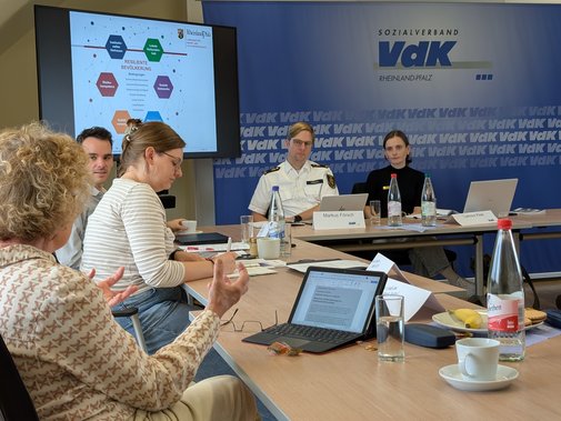 Frauen und M&auml;nner in der Diskussion an Tischen.