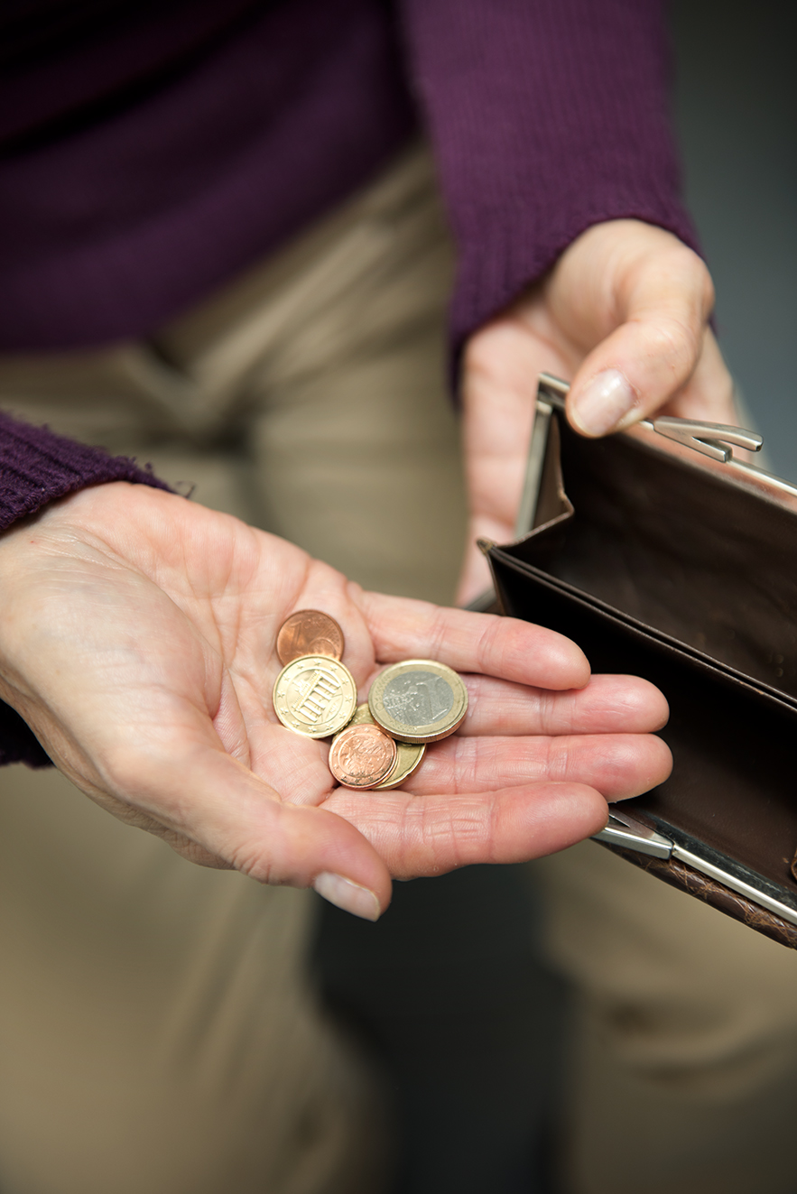 H&auml;nde einer Frau halten eine Geldb&ouml;rse auf, auf der Handfl&auml;che der einen Hand liegen wenige M&uuml;nzen. 