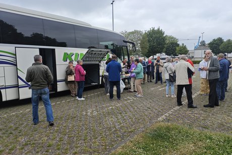 Mitglieder stehen draußen vorm Bus und essen belegte Brötchen