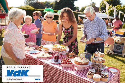 Menschen unterschiedlicher Generationen an einem Kuchenbuffet.