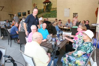 Markus Stumm steht an einem Tisch an dem Mitglieder sitzen und unterhält sich mit ihnen.