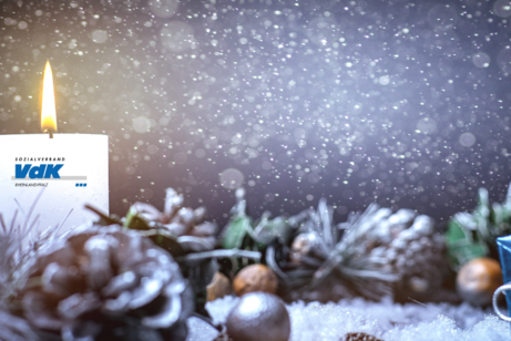 Kerze mit VdK-Logo und Weihnachtsdekoration.