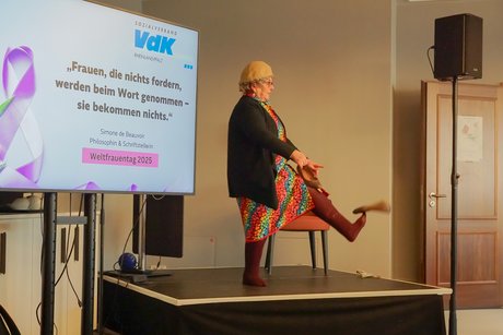 Comedian Alice Hoffmann im Kittel und mit Wollstrümpfen