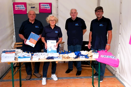 Eine Frau und drei Männer an einem Info-Stand.