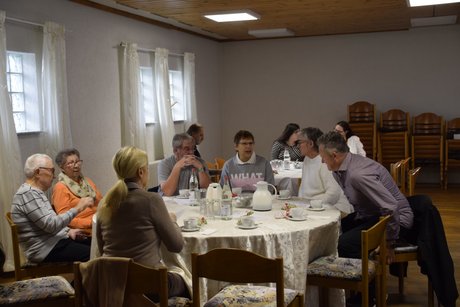 Menschen im Gespr&auml;ch an zwei runden Tischen