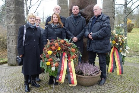 Kranzniederlegung am Ehrenmal Menschen mit Kranz vor Ehrenmal