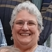 Eine l&auml;chelnde Dame mit Brille und blauer Halskette