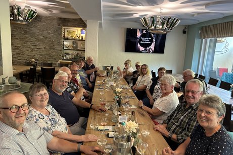 Eine Gruppe von Menschen sitzt an einem gedeckten Tisch.