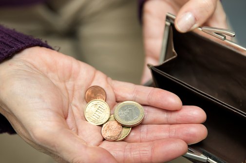 H&auml;nde einer Frau halten eine Geldb&ouml;rse auf, auf der Handfl&auml;che der einen Hand liegen wenige M&uuml;nzen. 