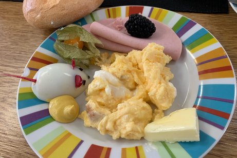 dekorierter Fr&uuml;hst&uuml;cksteller mit Maus aus halbem Ei und Radieschen-St&uuml;cken als Ohren und Schwanz