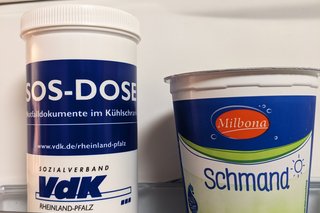 Neben einem Schmandbecher sieht man die SOS-Dose vom VdK