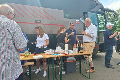 Menschen vor Bus mit Br&ouml;tchen in der Hand