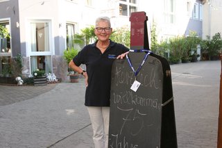 Schriftführerin des OV steht neben einer Willkommen Tafel.