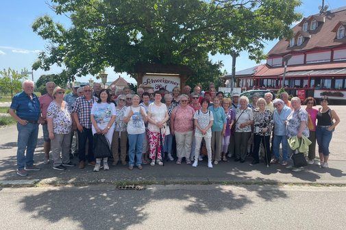 Eine Gruppenfoto von Männer und Frauen vor einem Baum.