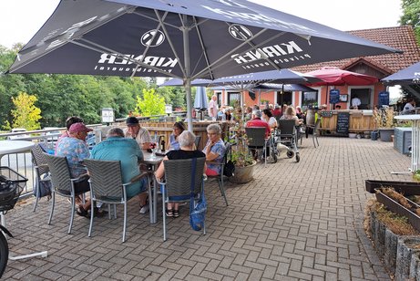 Mehrere Personen sitzen auf der Restaurant-Terrasse.