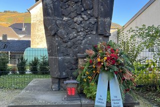 Das Bild zeigt die Skulptur aus Sandstein, welche zu Ehren der Opfer der beiden Weltkriege neben der Pfarrkirche Dernau errichtet wurde.