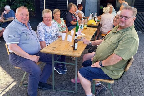 1. Bild von Mitgliedern mit Getränken am Tisch.