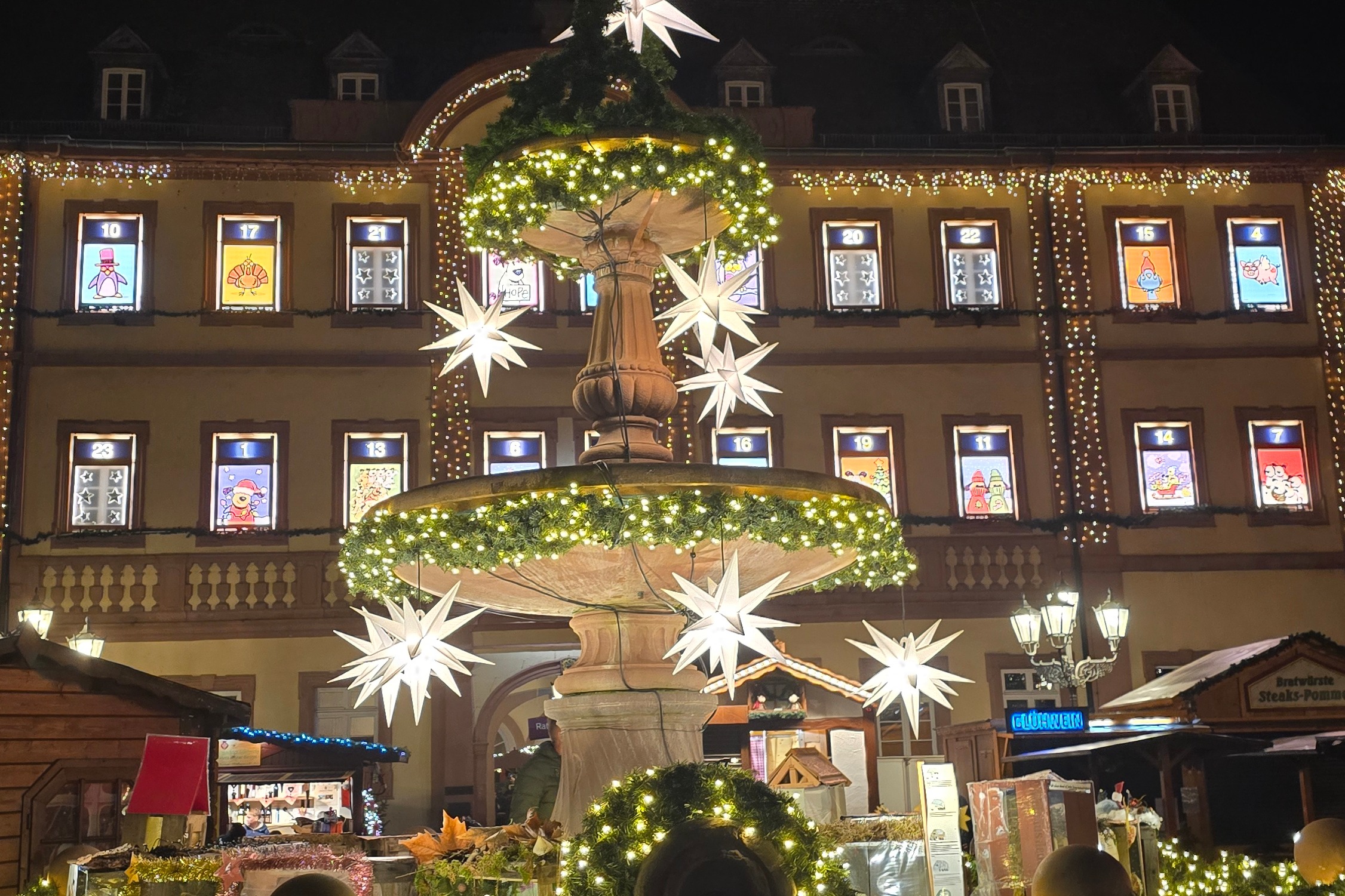 Brunnen mit Lichtketten und Haus mit beleuchteten Fenster