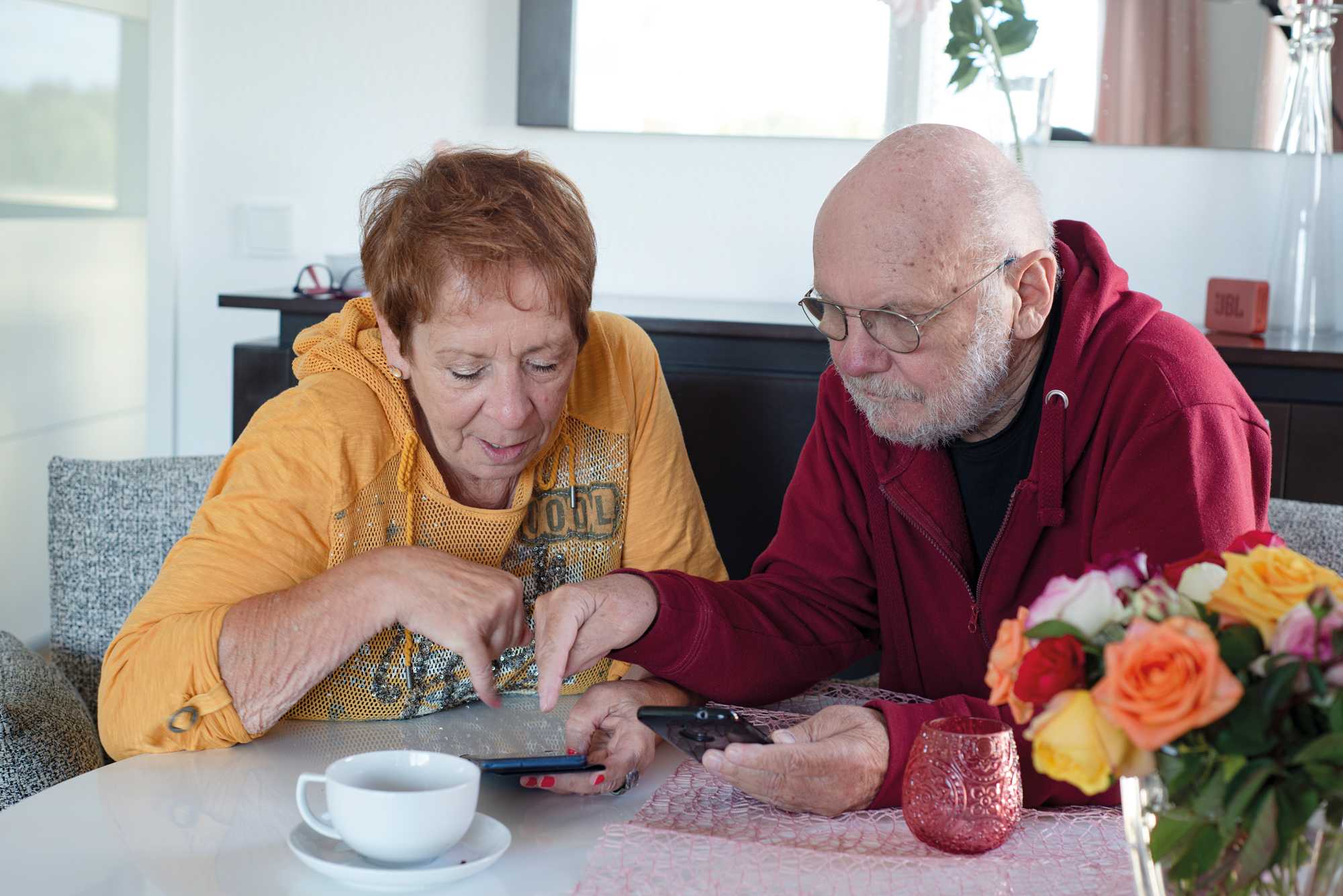 Eine rüstige Frau und ein Senior beugen sich gemeinsam über ein Tablet