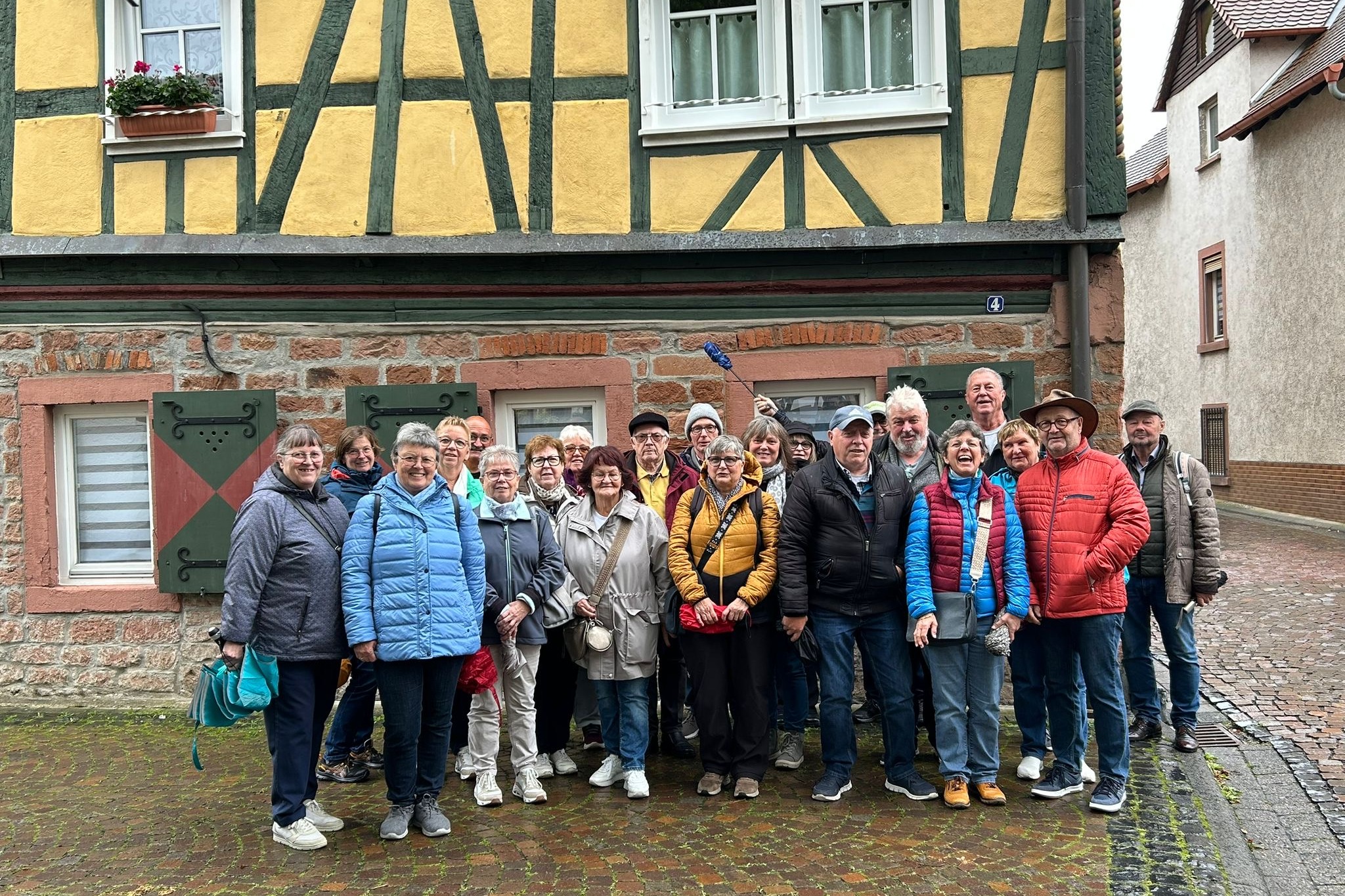 eine Gruppe Menschen steht vor einem Fachwerkhaus