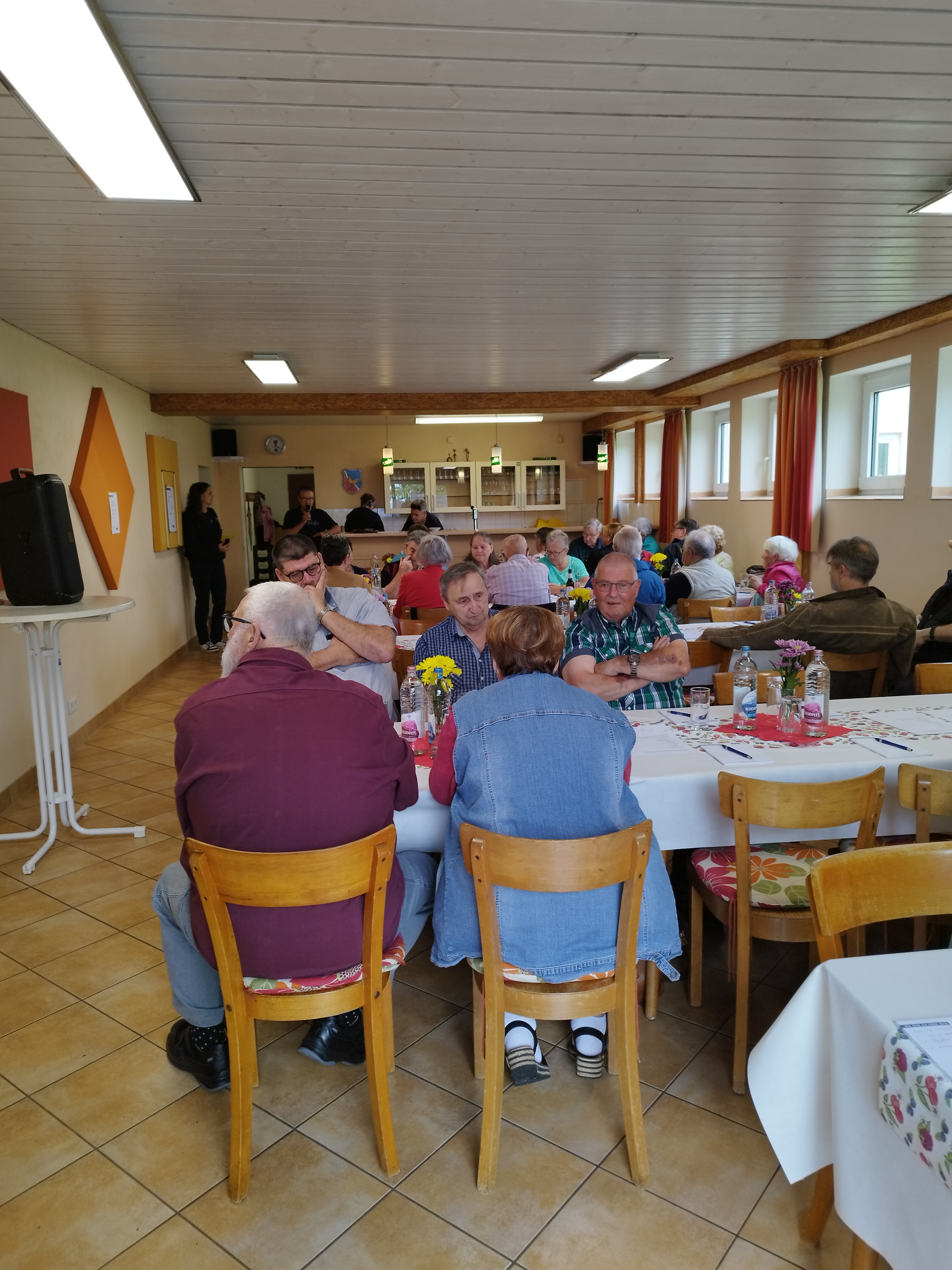 Viele Mitglieder sitzen an Tischen und feiern