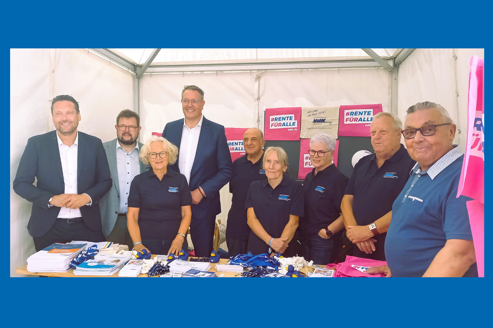 Acht Frauen und Männer stehen mit Werbemitteln in einem Stand.